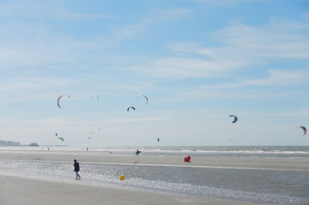 Kitesurfers boven het strand en de zee bij Zeebrugge